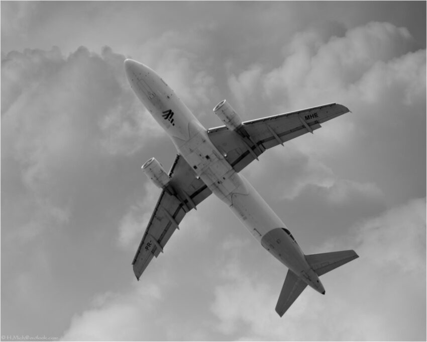 StudioOne Repo – Foto em preto e branco de um avião voando no céu.