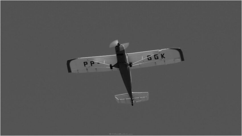 StudioOne Repo – Fotografia PB de um avião voando no céu.
