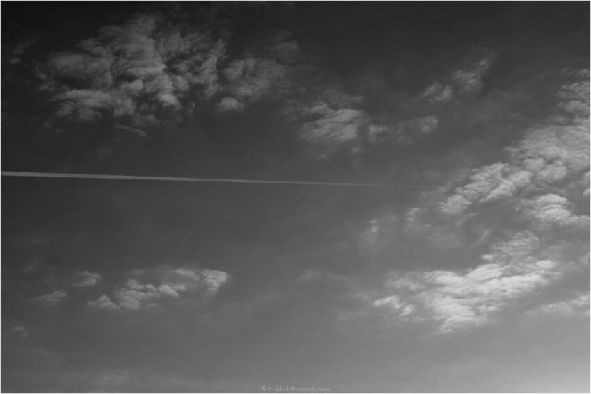 StudioOne Repo – Fotografia PB de um avião voando no céu.
