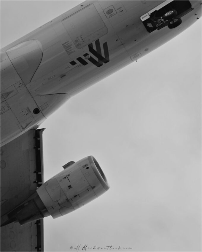 StudioOne Repo – Fotografia PB de um avião voando no céu.