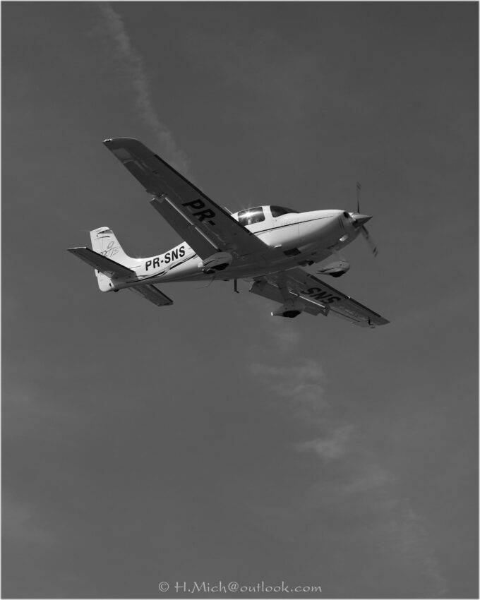 StudioOne Repo – Fotografia PB de um pequeno avião voando no céu.