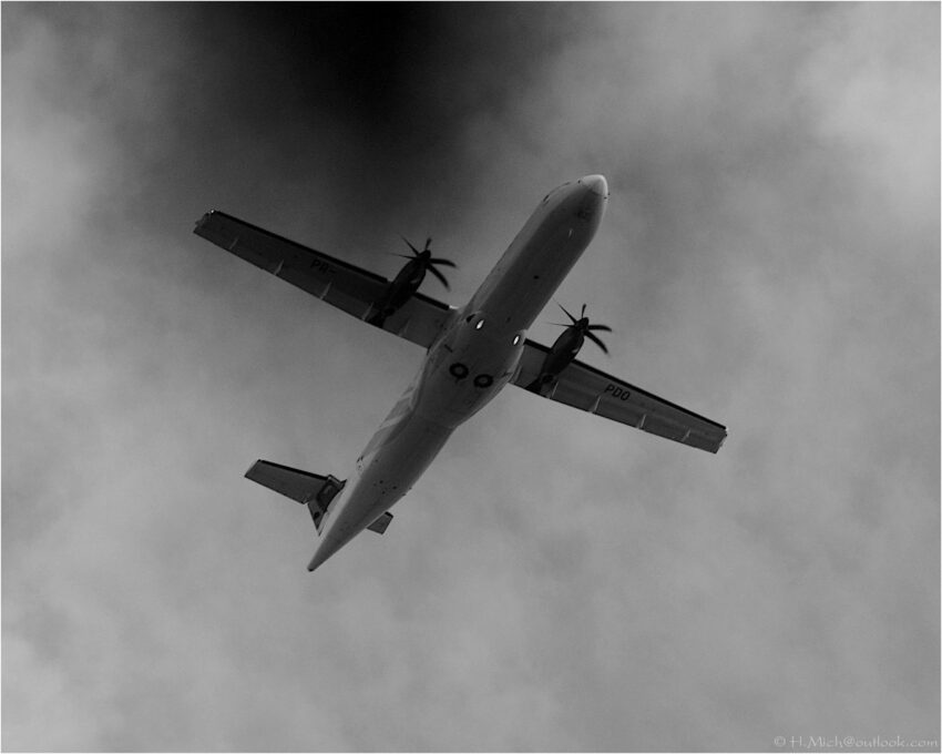 StudioOne Repo – Foto em preto e branco de um avião voando no céu.