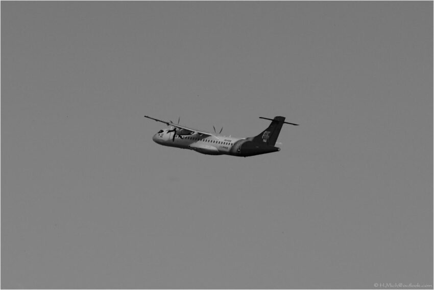 StudioOne Repo – Uma Foto um avião que está voando no céu em preto e branco.